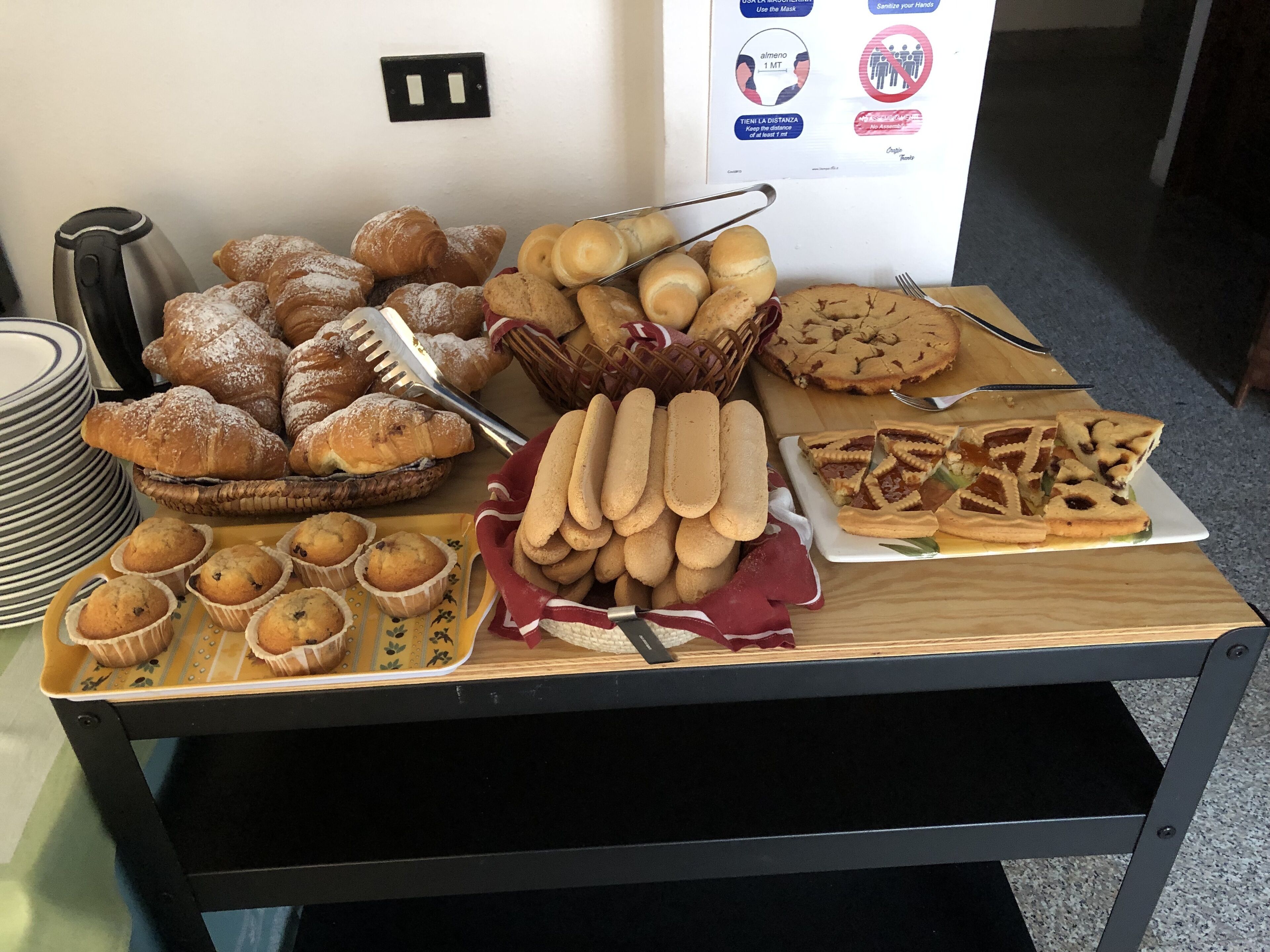 A buffet table with various baked goods including pastries, muffins, and cookies.