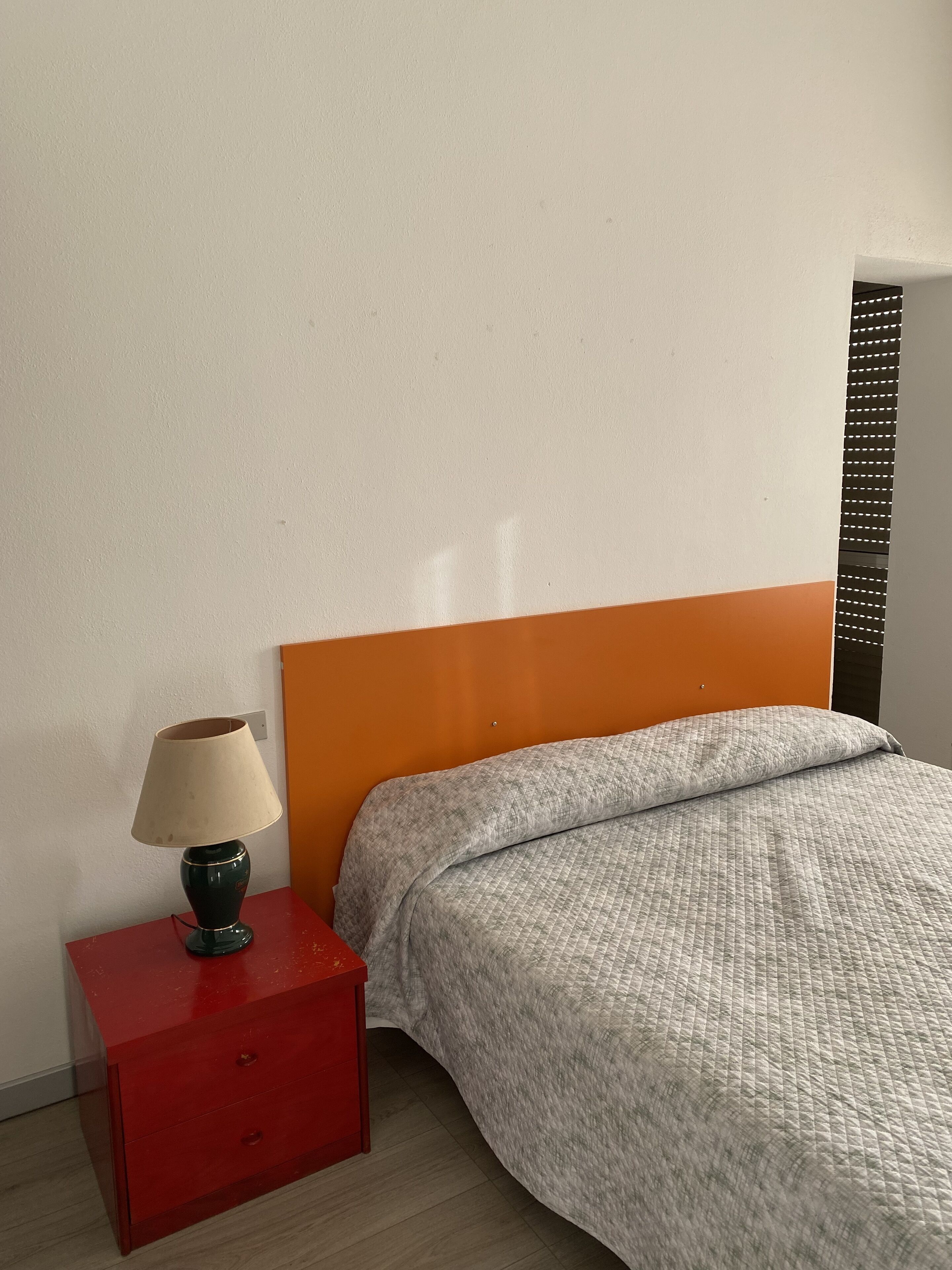 Een slaapkamer met een bed, nachtkastje en lamp.