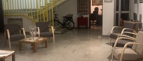 A spacious lobby with a staircase, seating area, and a bicycle.