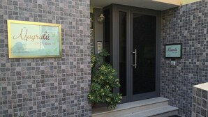 Entrada de un edificio con una puerta oscura, paredes con azulejos y dos letreros enmarcados.