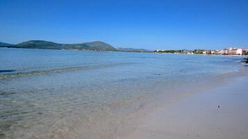 Perto da praia, areia branca, guarda-sóis, toalhas de praia