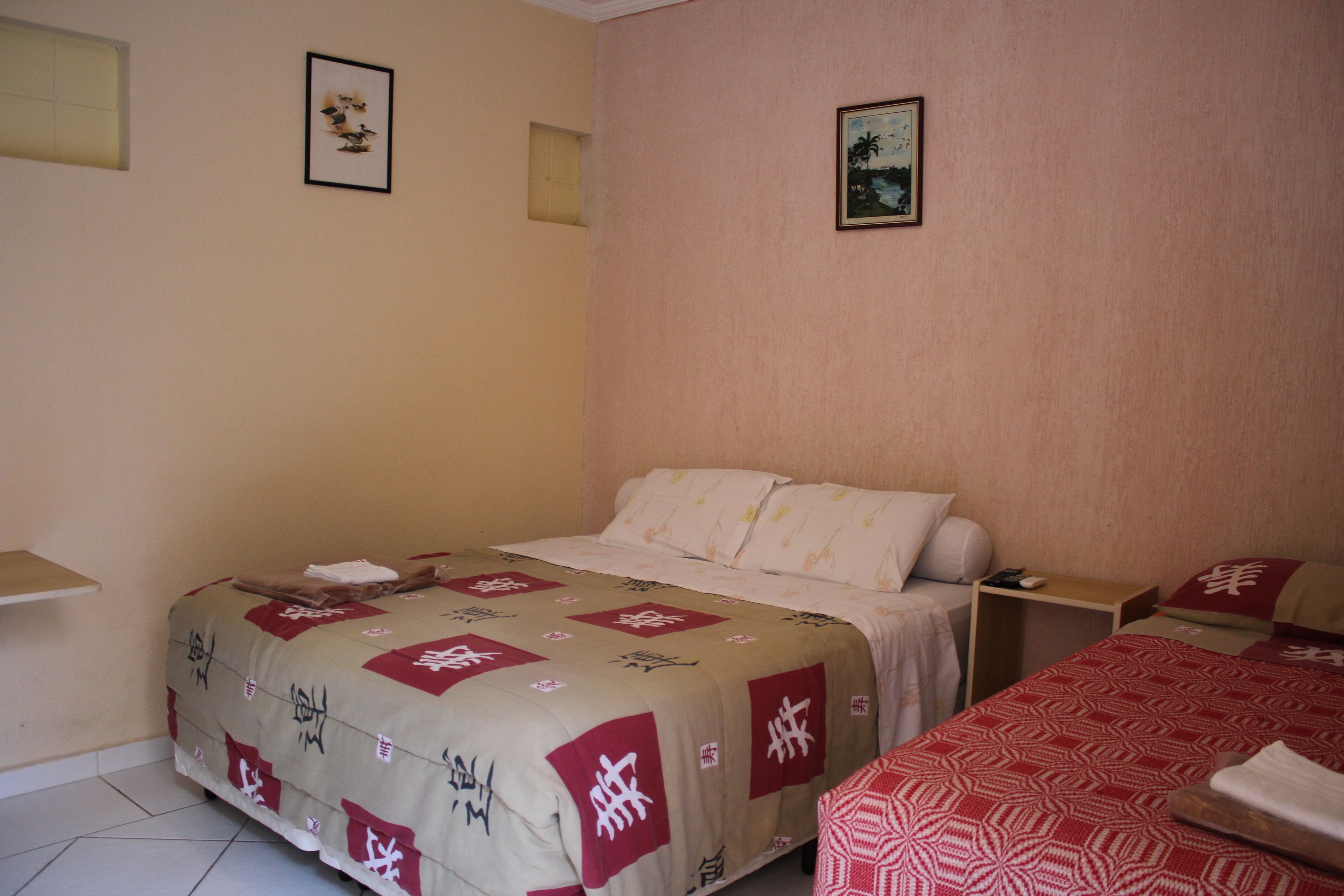 A hotel room with a bed, bedside table, and a small desk.