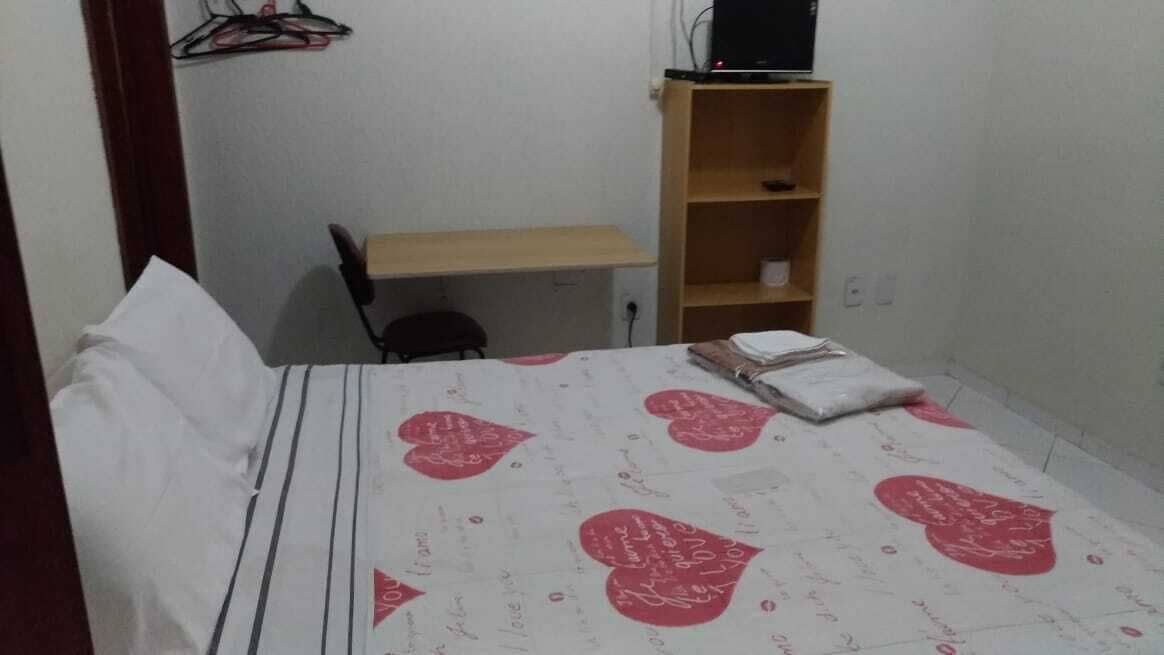 A bedroom with a bed, a desk, and a chair.
