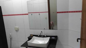 Un baño con un lavamanos blanco, un espejo y una pared con azulejos rojos.