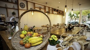 A restaurant interior with a wooden table displaying a fruit basket, bread, and a potted plant. - I Hotel (Amsterdam)