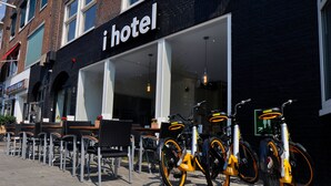 A hotel with outdoor seating and multiple bicycles parked outside. - I Hotel (Amsterdam)