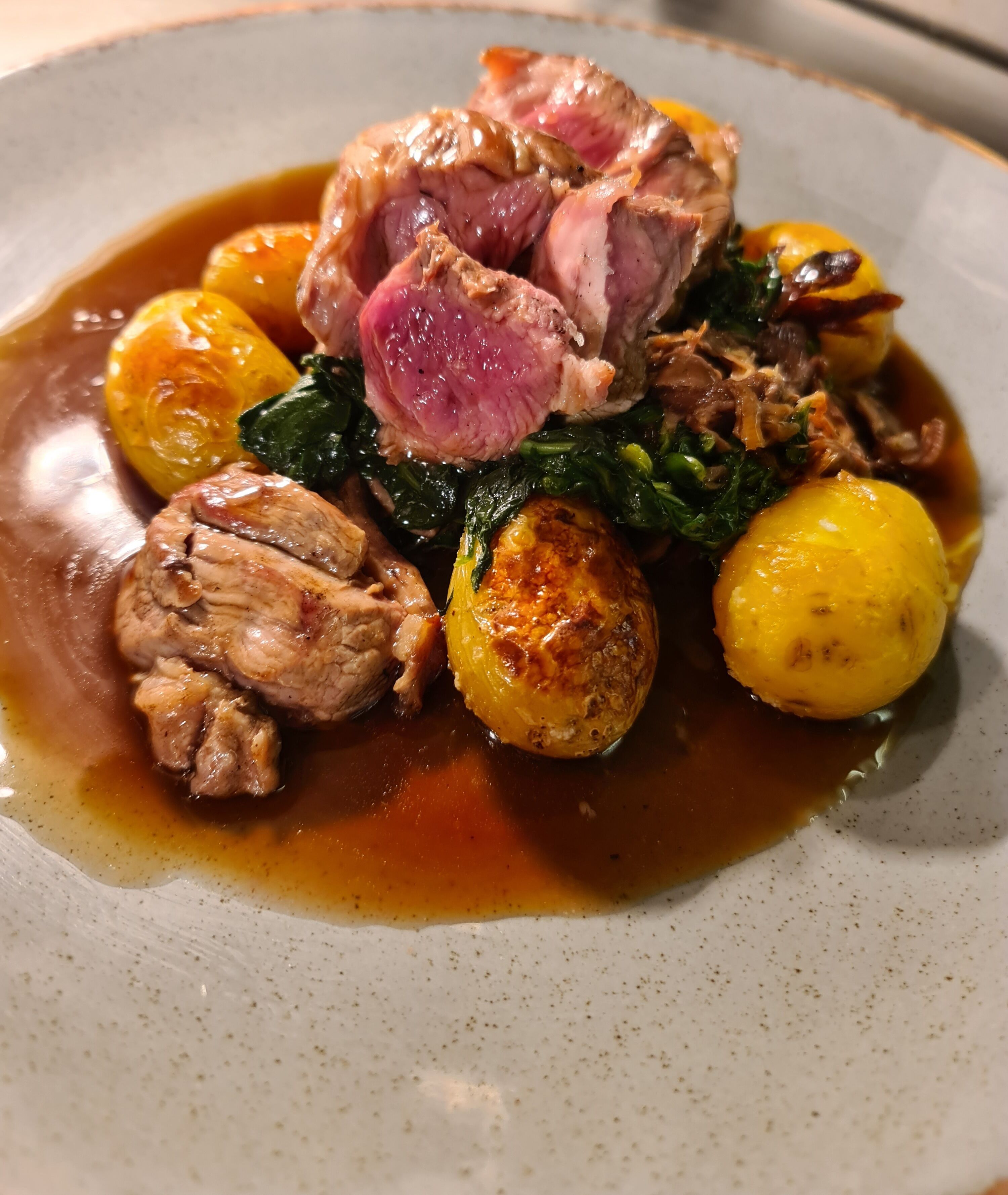 Une assiette de nourriture composée de viande, de pommes de terre et de légumes verts.