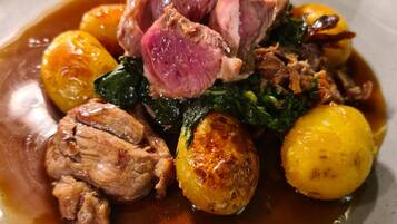 Une assiette de nourriture composée de viande, de pommes de terre et de légumes verts.