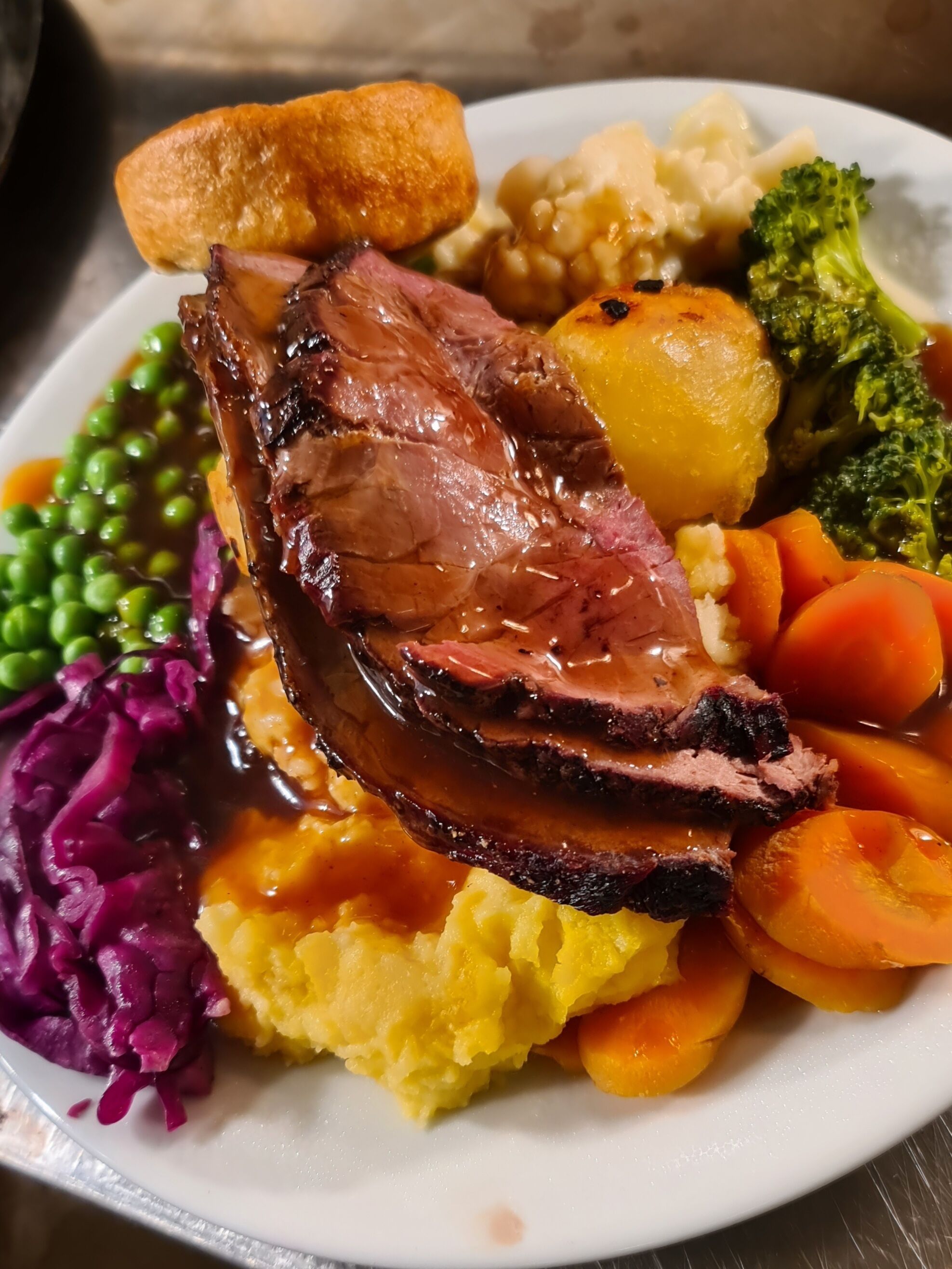Une assiette de rosbif accompagné de légumes et de Yorkshire pudding.