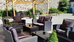 An outdoor seating area with wicker furniture and a stone wall backdrop.