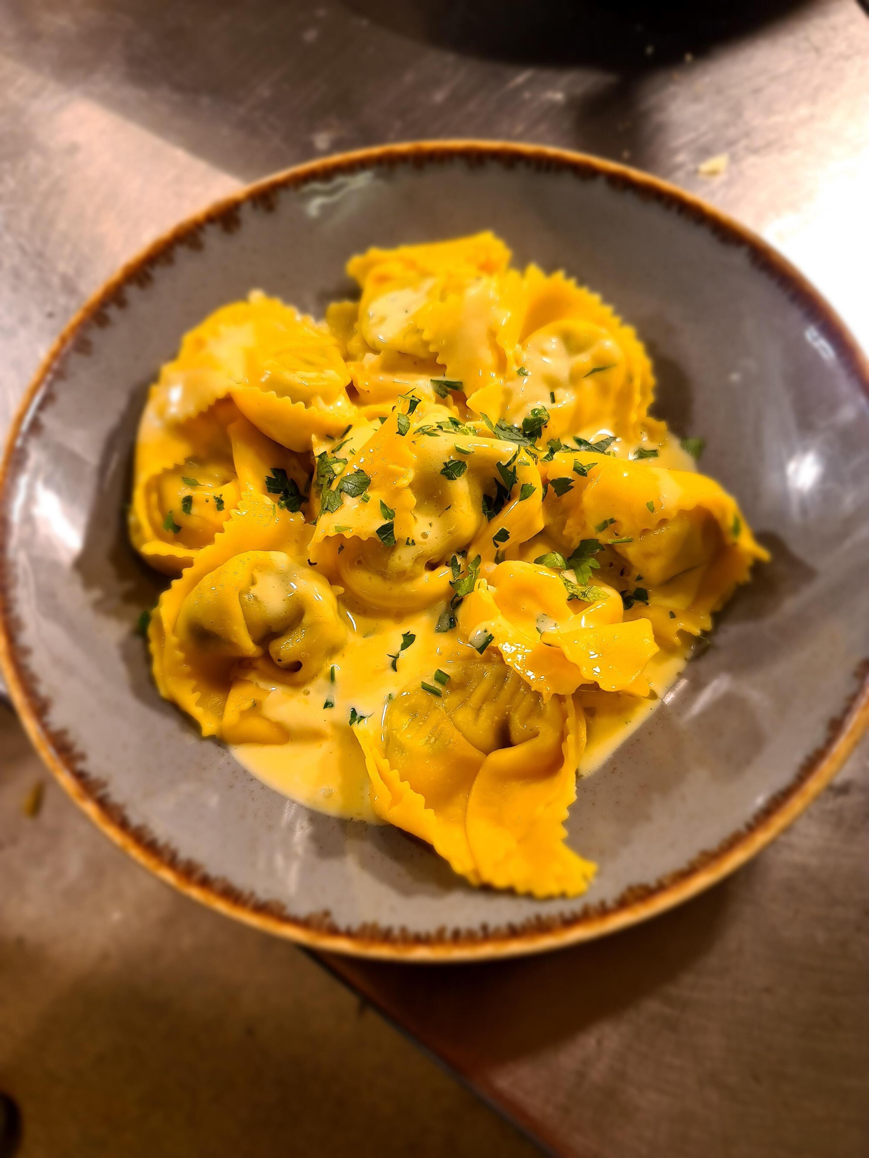 A plate of ravioli with a creamy sauce and garnished with herbs.