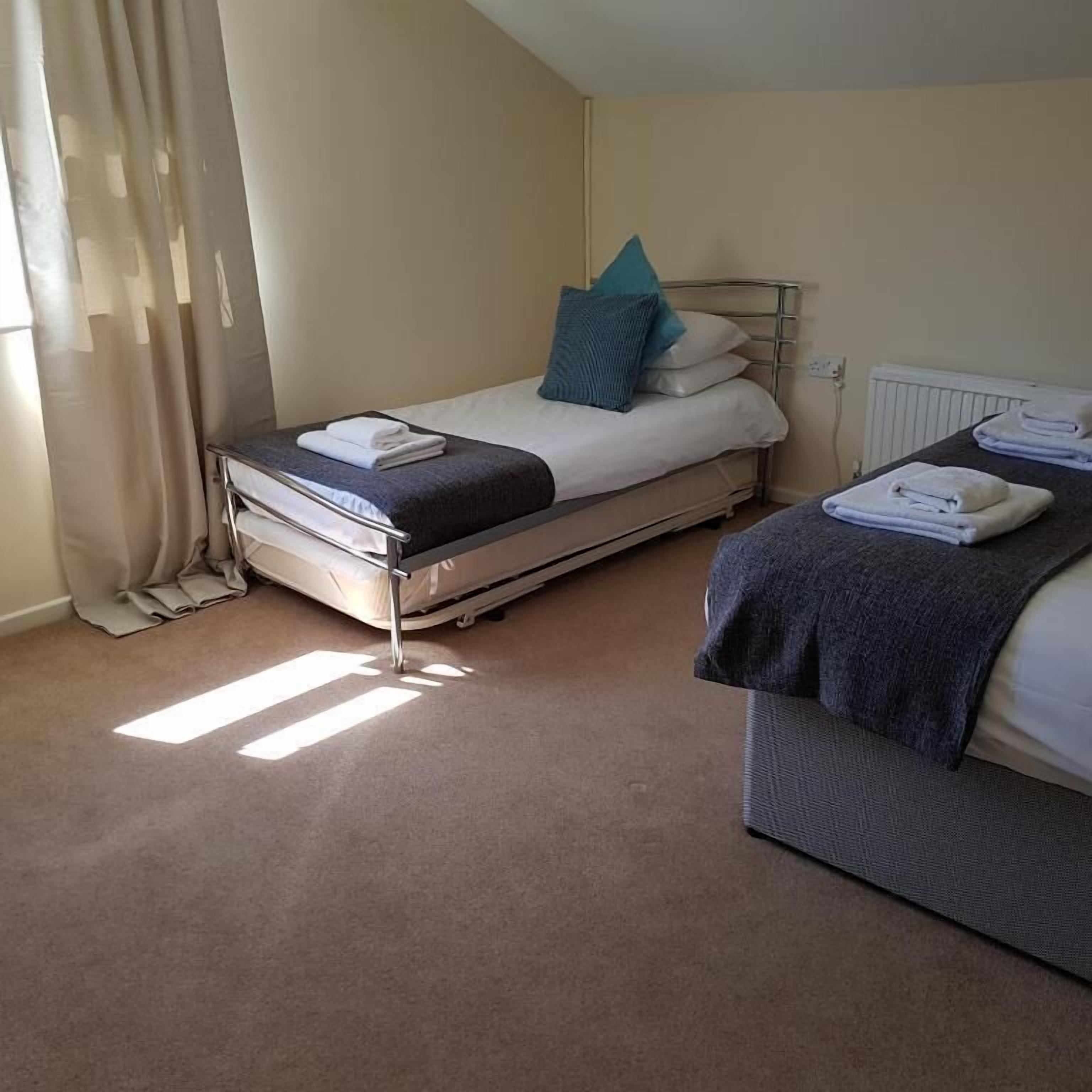 A hotel room with two beds, a radiator, and a window with curtains.