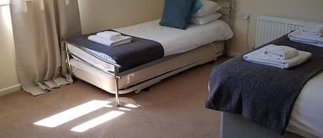 A hotel room with two beds, a radiator, and a window with curtains.