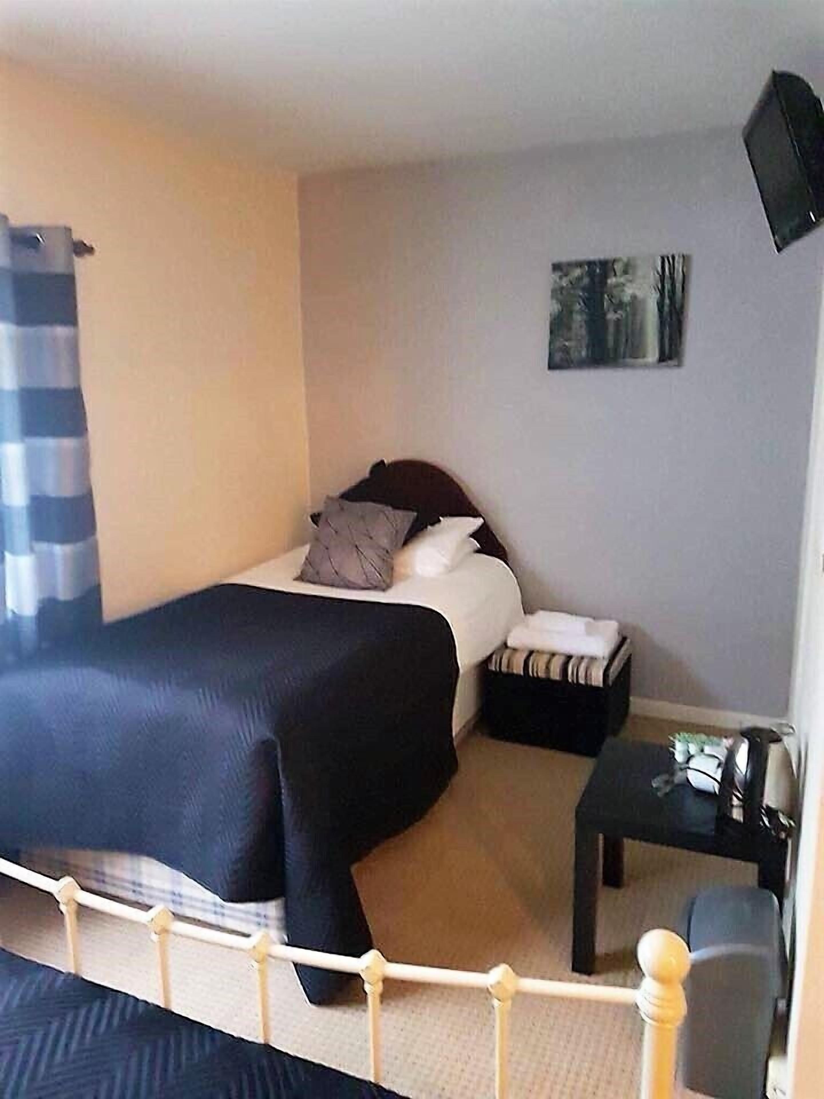 A hotel room with a bed, a bedside table, a chair, and a painting on the wall.