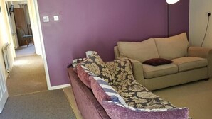 A living room with a sofa, a patterned throw, and a lamp.