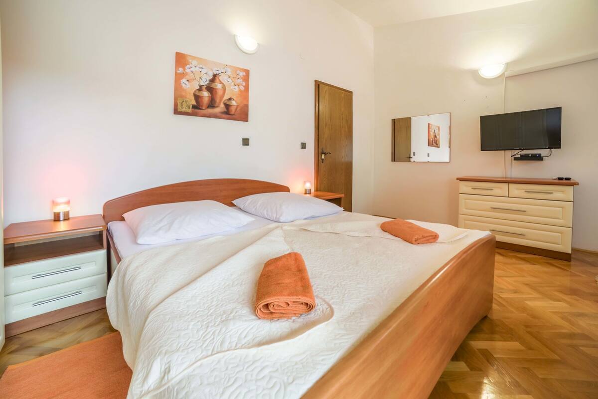 Ein Schlafzimmer mit einem Bett, Nachttischen, einem Fernseher und einer Kommode.