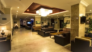 A spacious lobby with a high ceiling, multiple seating areas, and a television. - Grand Hotel Terme (Kirsehir)