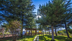 A gazebo in a park with a stone path leading to it, surrounded by trees and a clear sky. - Grand Hotel Terme (Kirsehir)