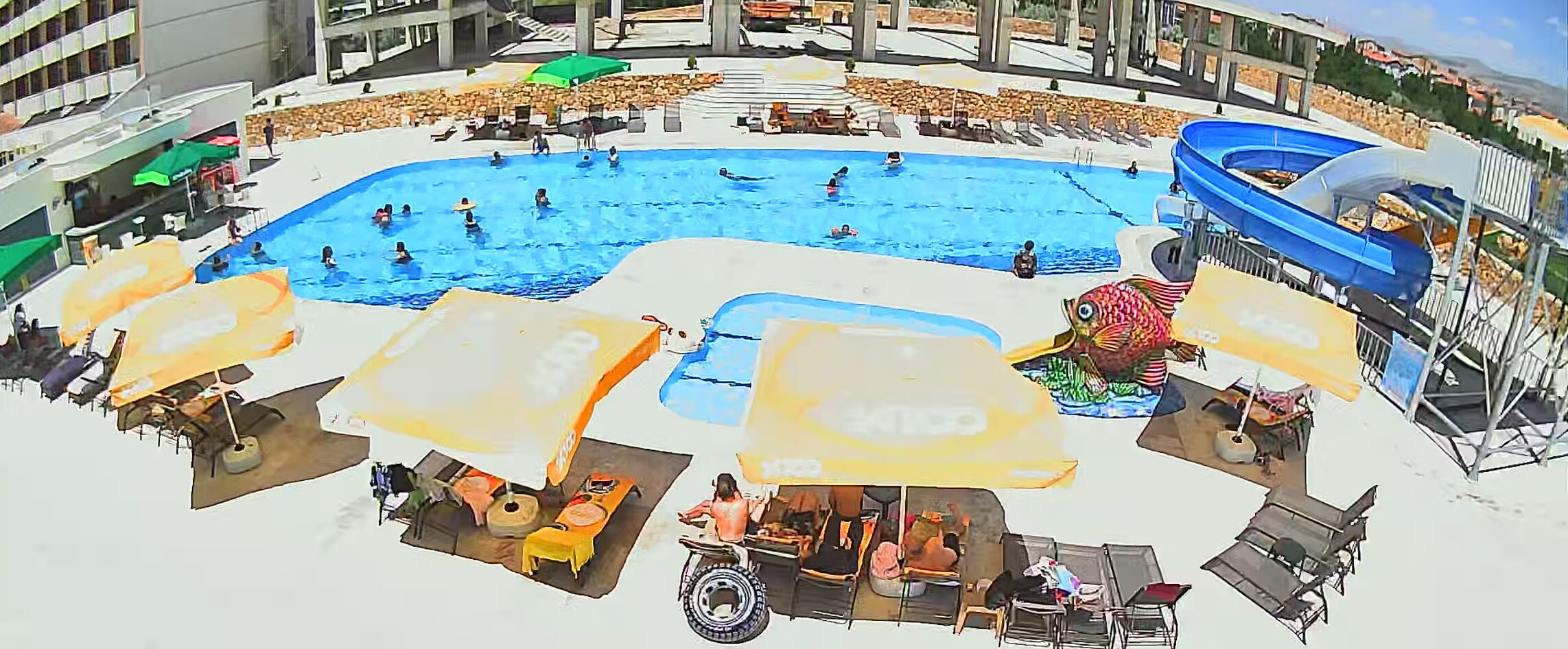 Une grande piscine extérieure avec plusieurs couloirs de nage, entourée de chaises longues et de parasols.