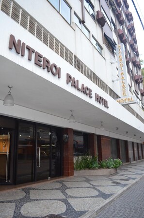 Het uiterlijk van Hotel Niteroi Palace, met een moderne gevel, grote glasramen en een betegeld entreegebied.