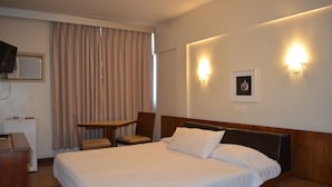 A hotel room with a large bed, a desk, a chair, and a television. - Niterói Palace Hotel (Niteroi)