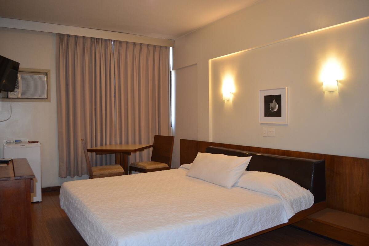 A hotel room with a large bed, a desk, a chair, and a television.