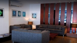 A modern living room with a sectional sofa, a small table, and framed artwork on the wall. - Niterói Palace Hotel (Niteroi)