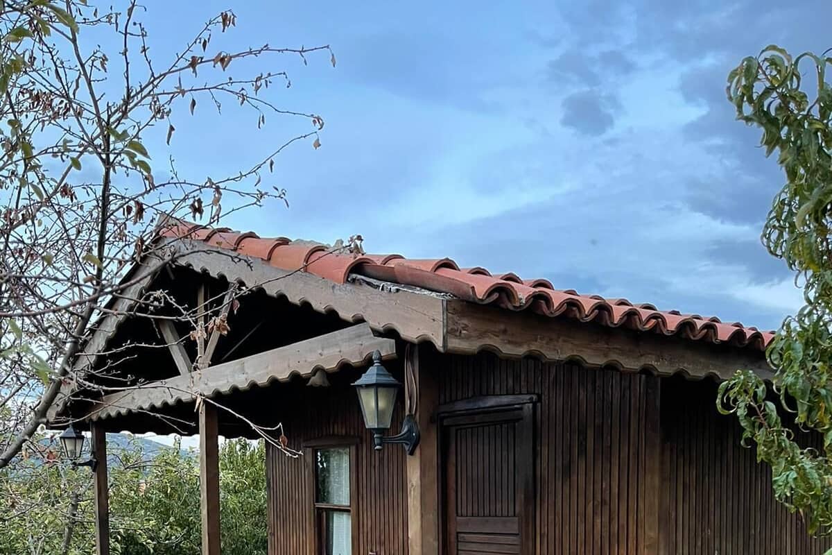 Um edifício rústico de madeira com varanda, degraus de pedra e uma mesa de madeira com cadeiras.