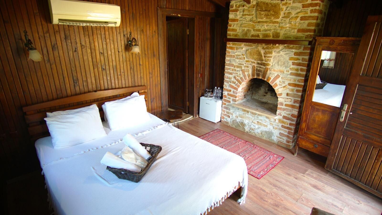Una habitación de hotel con una cama, una chimenea de piedra y paredes de madera.