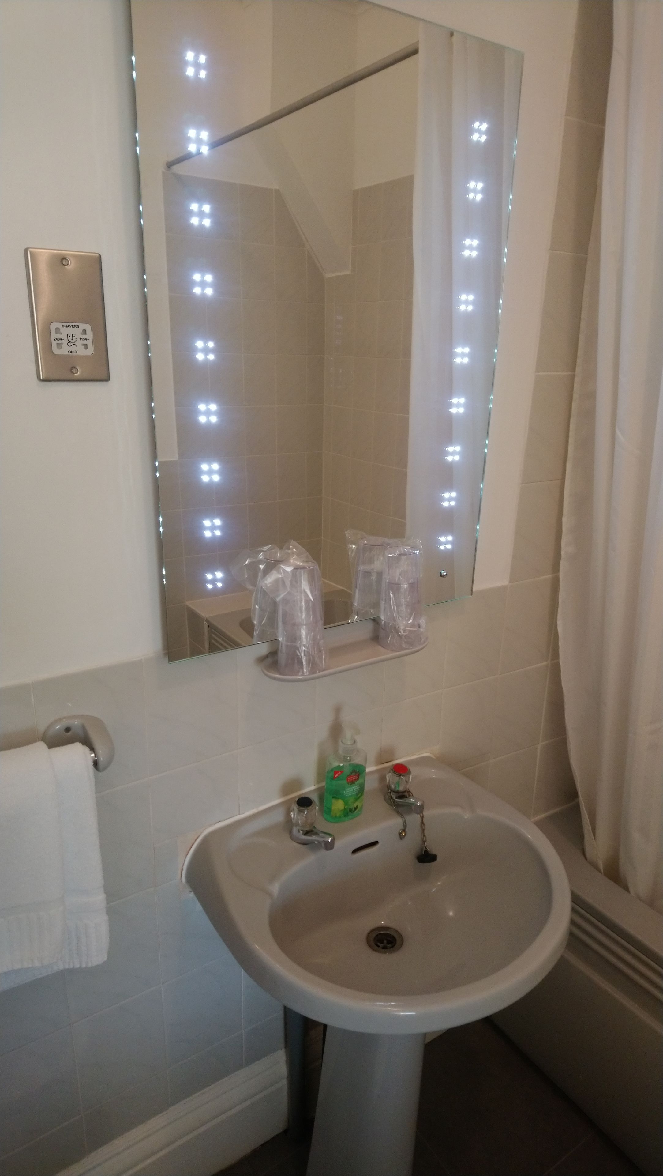 A bathroom with a sink, mirror, and lights.