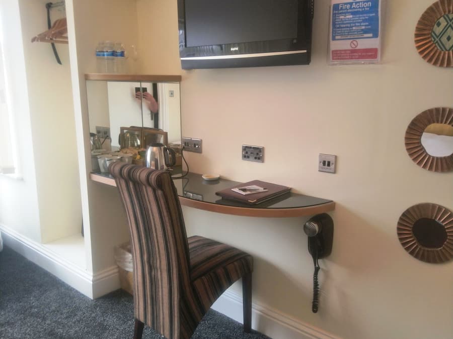 A small office space with a desk, chair, television, and a fire action sign.