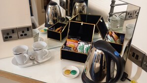 Et hotelværelse med minibar, kaffemaskine og et spejl, der viser værelsets indretning.