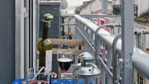 Un balcon avec une table dressée pour deux personnes, comprenant des verres à vin, une bouteille et une lanterne.