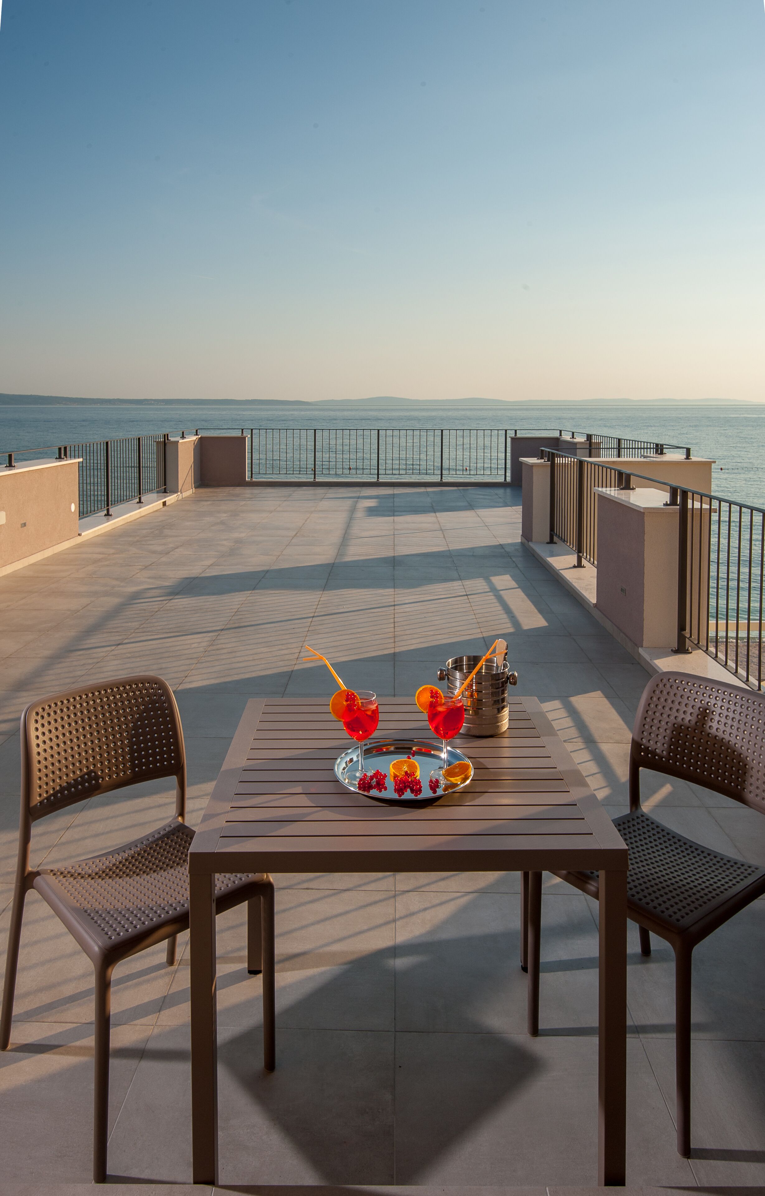 A terrace with a table set for two, overlooking a body of water.