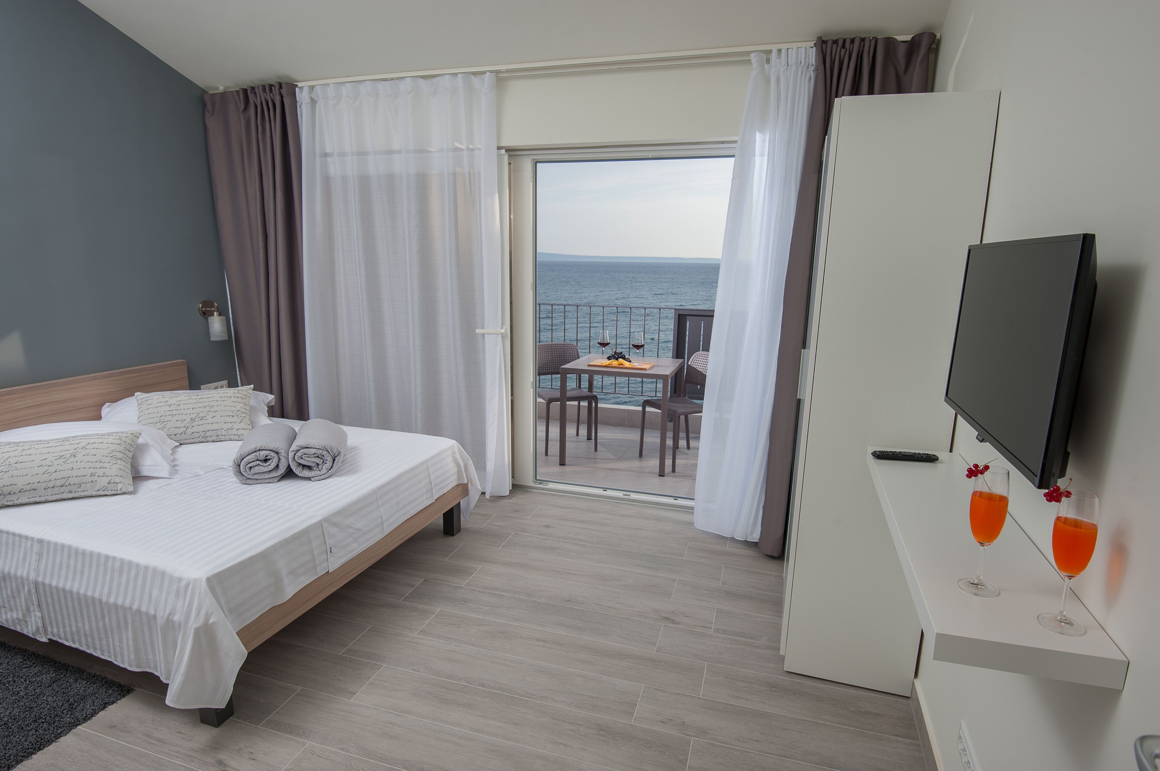 A hotel room with a bed, a TV, and a balcony with a table and chairs.