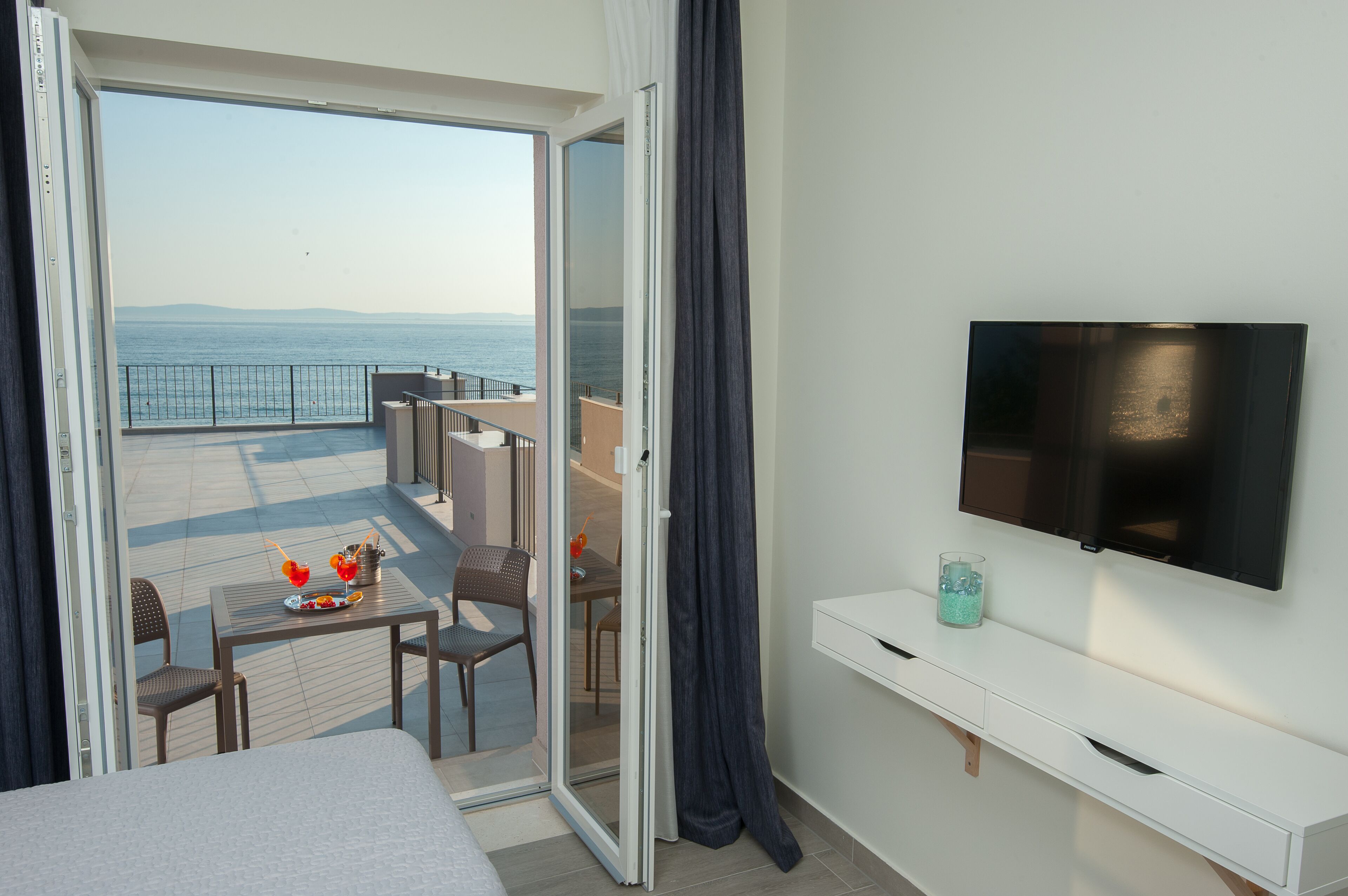 Un balcon avec une table, des chaises et un téléviseur.