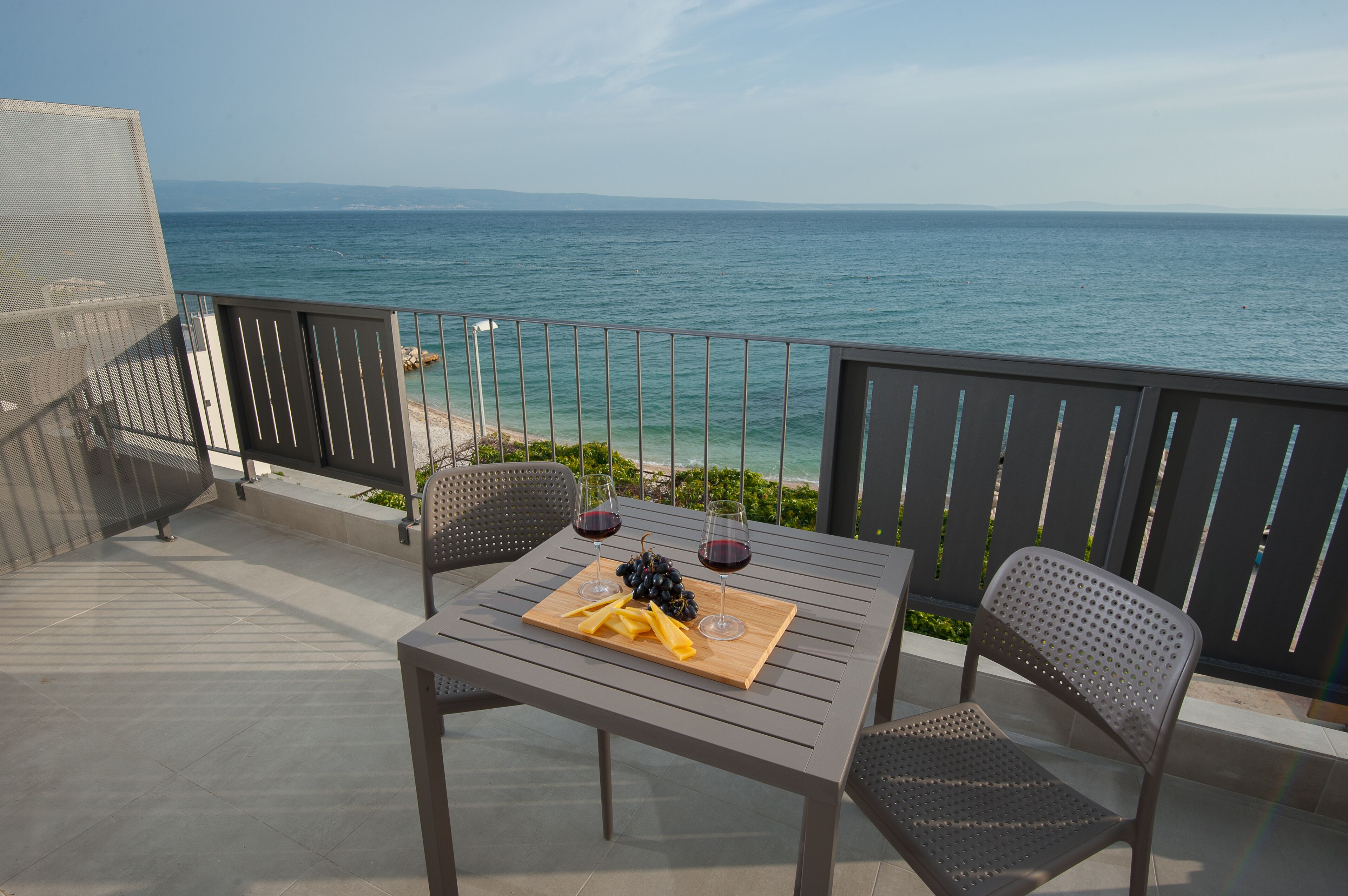 A balcony with a table set for two, overlooking the sea.
