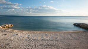 Una playa con agua cristalina, una orilla arenosa y un espigón rocoso.