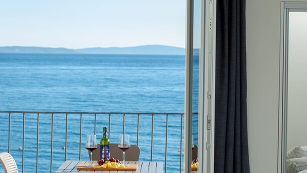 Un balcón con una mesa dispuesta para dos personas, con vista al mar.