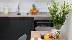 Una cocina moderna con un lavamanos, un cuenco de fruta, un jarrón de flores y alimentos para el desayuno sobre la encimera.