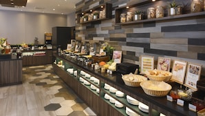 A buffet area with a variety of food items, a coffee machine, and a display of plates and bowls. - Nest Hotel Hakata Station (Fukuoka)