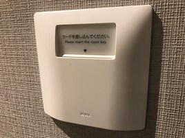 A wall-mounted electronic device with Japanese text instructing to insert a room key.