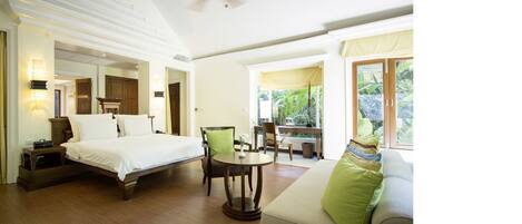 A hotel room with a bed, a small table, a sofa, and a view of the outdoors.
