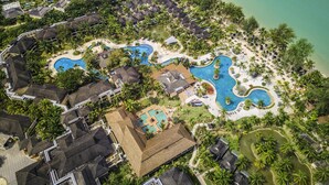 Vista aérea de un resort con varias piscinas, palmeras y propiedades frente al mar.