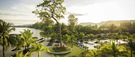 Un resort con piscina, palmeras y vista al agua.