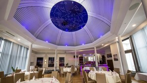 A restaurant with round tables, white tablecloths, and a ceiling with a circular design. - Hotel Am Schloss Aurich (Aurich)