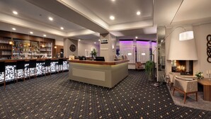 A hotel reception area with a bar, seating, and a reception desk. - Hotel Am Schloss Aurich (Aurich)