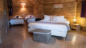 A cozy cabin-style room with three beds, wooden walls, and a sloped ceiling. - Domaine de la Boulaie (Treize-Vents)