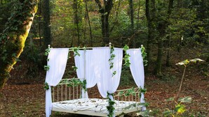A bed in a forested area with white drapes and greenery. - Domaine de la Boulaie (Treize-Vents)