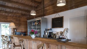 A rustic bar area with wooden chairs, a white vase with flowers, a coffee machine, and a chalkboard with 'Bonjour' written on it. - Domaine de la Boulaie (Treize-Vents)